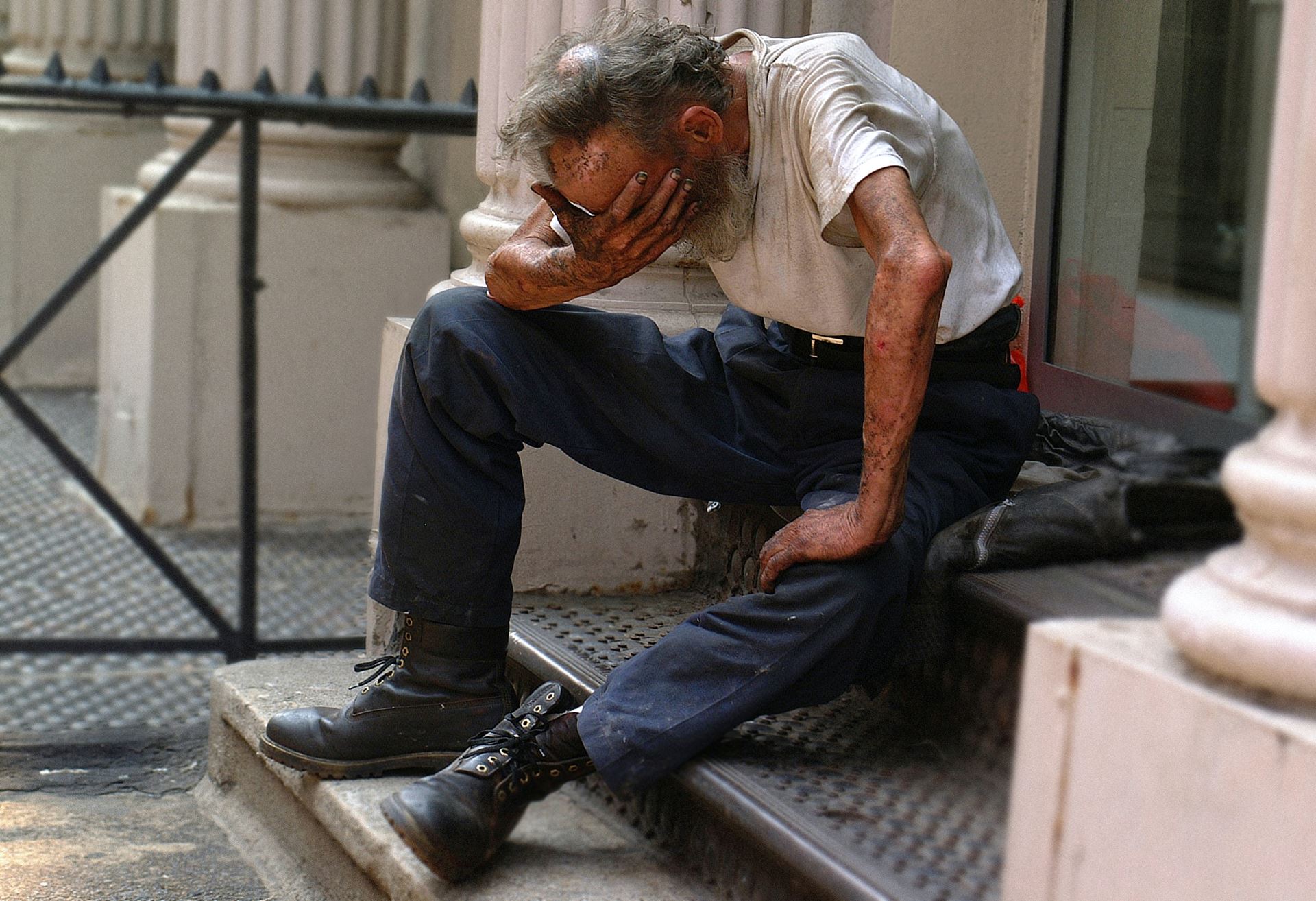 a man sat bent over and looking down, his head in one of his hands