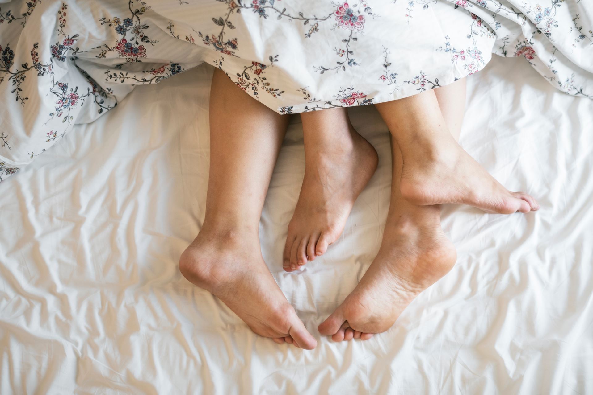 a couples feet at the end of a bed