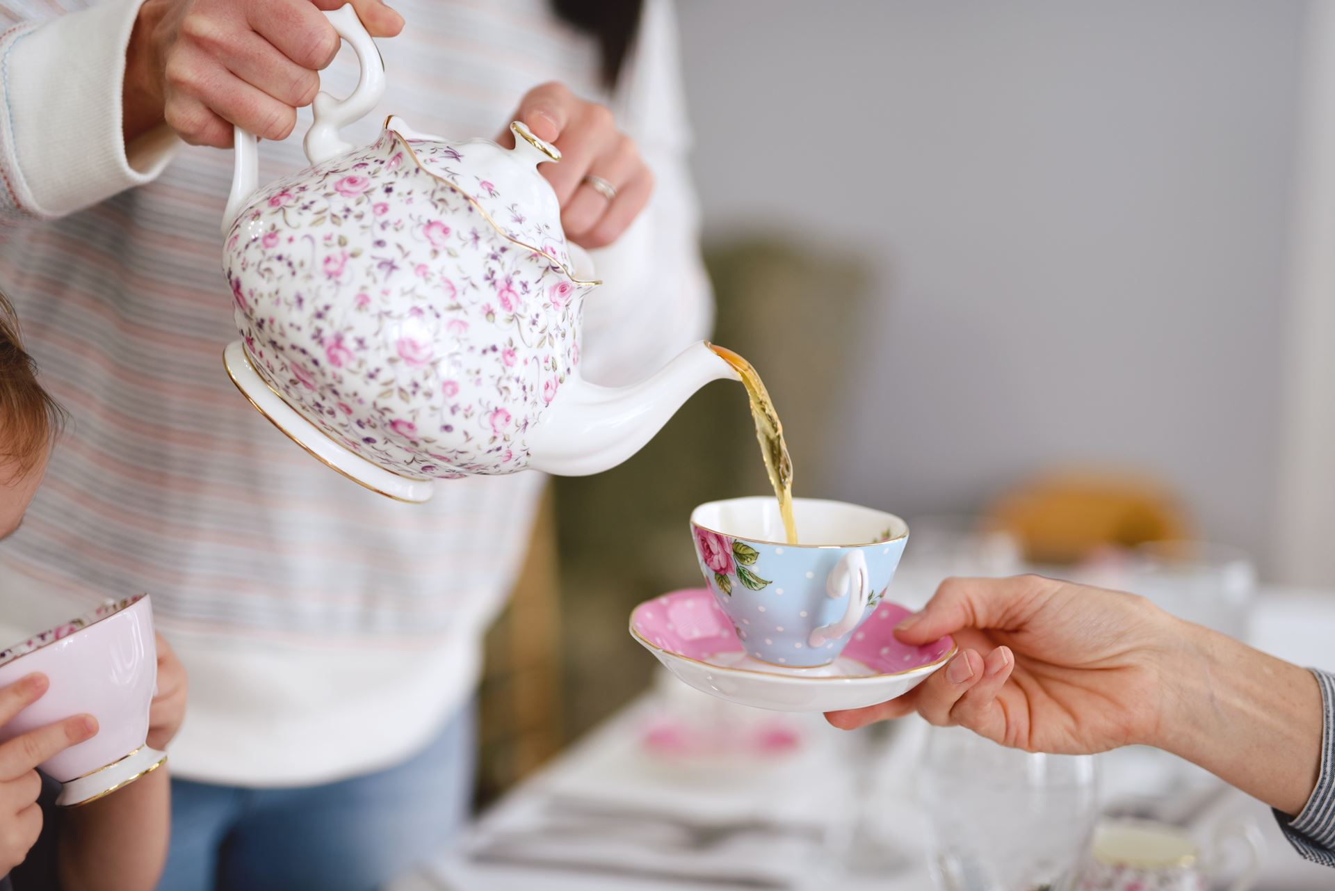 a person pouring a cup of tea from a teapot