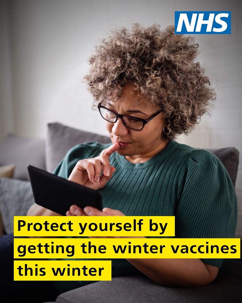 a middle aged woman looking at her mobile device, the NHS logo and the words Protect yourself by getting the winter vaccines this winter